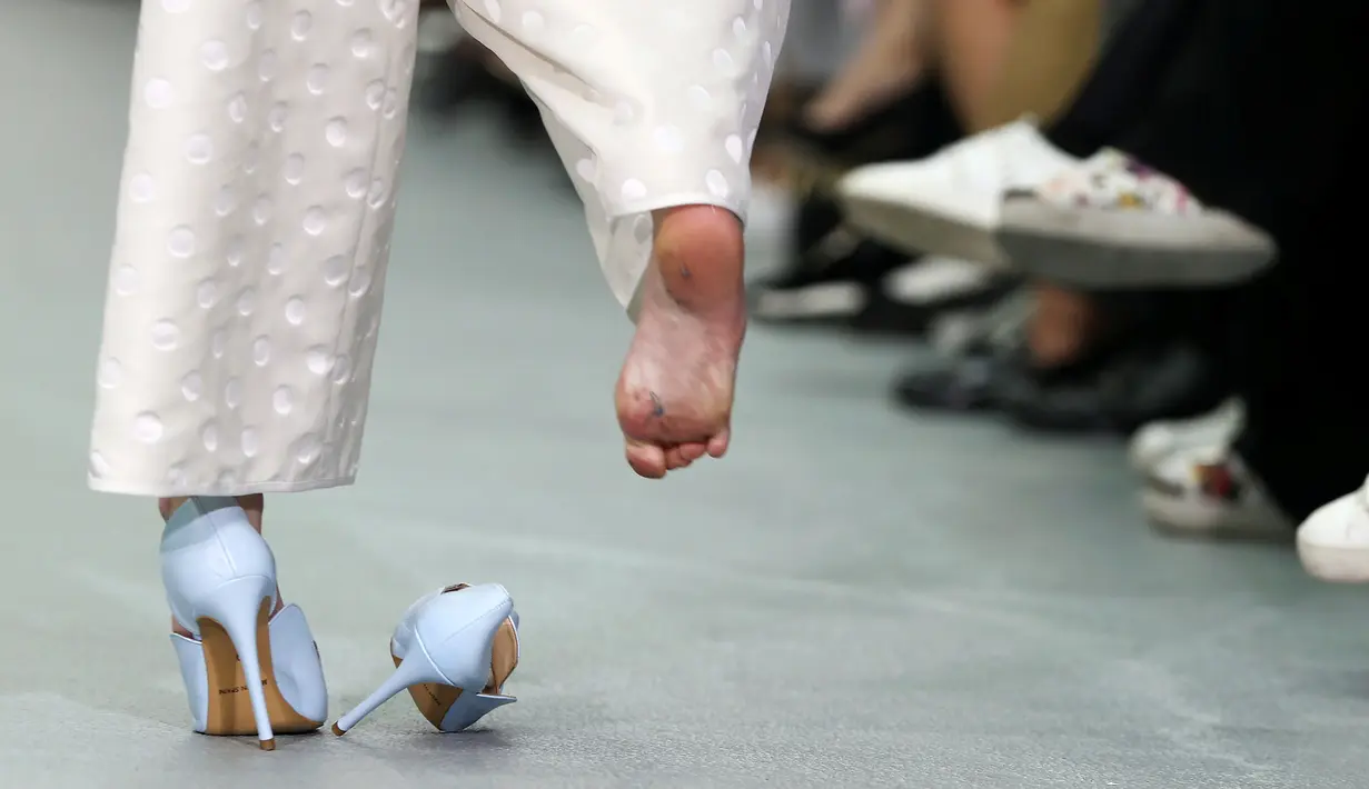 Sepatu seorang model terlepas saat memperagakan busana rancangan Emilio De la Morena pada London Fashion Week 2017 di Inggris, Selasa (20/9).  Meski sepatunya terlepas, model ini tetap percaya diri berjalan dengan sebelah alas kaki. (REUTERS/Neil Hall)