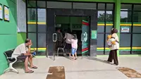 Suasana di depan sebuah fasilitas kesehatan di Gunungkidul, Sebuah tanda di sisi kanan pintu mengingatkan "KAWASAN WAJIB MASKER", menunjukkan bahwa fasilitas ini masih menerapkan protokol kesehatan.