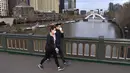 Orang-orang dengan masker berjalan di jembatan yang melintasi Sungai Yarra pada hari pertama wajib masker, di Melbourne Kamis (23/7/2020). Penduduk kota terpadat kedua di Australia, Melbourne, diwajibkan mengenakan masker saat meninggalkan rumah untuk mencegah penyebaran COVID-19. (William WEST/AFP)