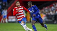 Pemain Real Madrid, Ferland Mendy (kanan) mencoba menghindari pengawalan pemain Granada, Ruben Rochina, dalam lanjutan Liga Spanyol, Minggu (21/11/2021) malam WIB. (AP Photo/Fermin Rodriguez)