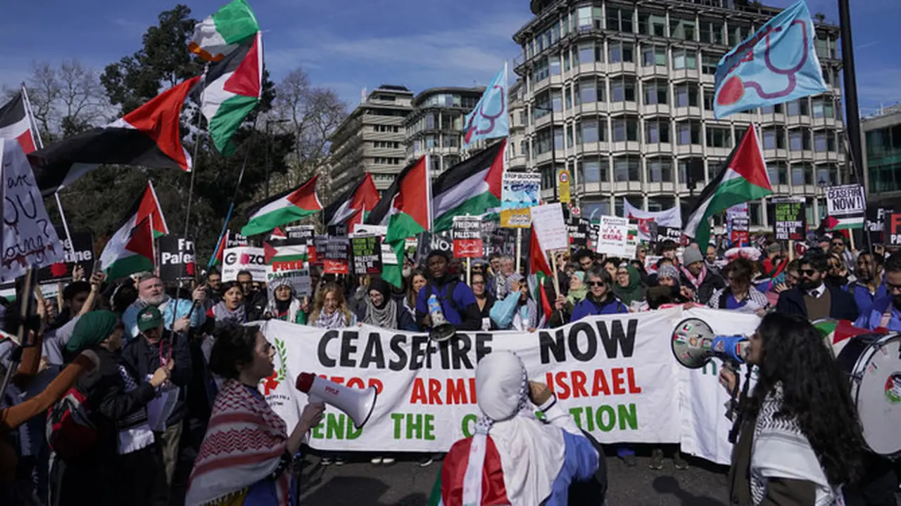 Demonstran memegang spanduk dan bendera saat mereka berkumpul menjelang pawai mendukung rakyat Palestina di Gaza, di London, pada 9 Maret 2024. (AP)