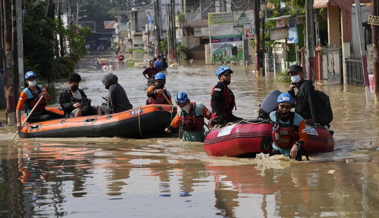 Warga duduk dalam perahu karet saat mereka mengungsi ke tempat yang lebih tinggi selama banjir di Bekasi, Jawa Barat, Kamis (17/2/2022). Hujan deras yang dikombinasikan dengan perencanaan pembuangan limbah kota yang buruk sering menyebabkan banjir besar. (AP Photo/Achmad Ibrahim)