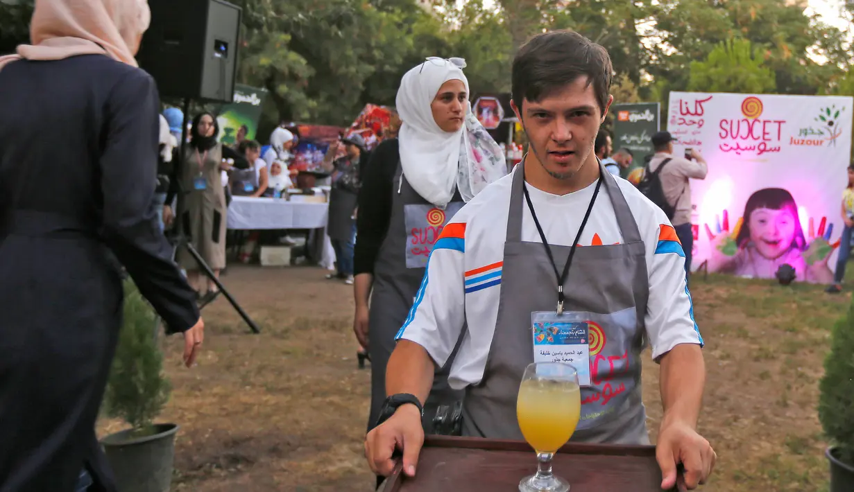 Seorang anak down syndrome Abdel Rahman membawa minuman di kedai kopi Sucet  selama festival "Sham gather us" di Damascus (11/7). Enam belas anak laki-laki dan perempuan down syndrome bekerja di Cafe Sucet melayani pelanggan. (AFP Photo/Louai Beshara)