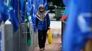 Seorang wanita berjalan di antara bendera partai politik, Kuala Lumpur, Malaysia, Senin (7/5). PM Malaysia Najib Razak akan bersaing dengan mantan mentornya, Mahathir Mohamad. (AP Photo/Aaron Favila)