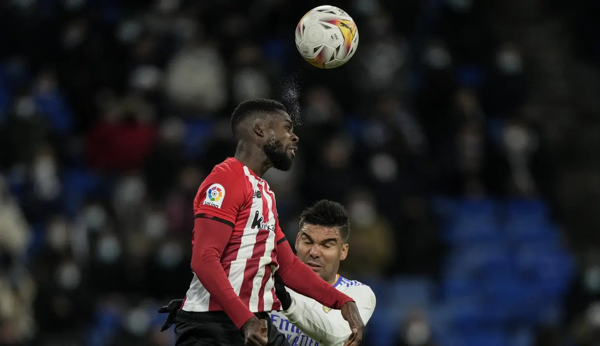 Gelandang Real Madrid, Casemiro berebut bola udara dengan pemain Athletic Bilbao, Inaki Williams pada pertandingan lanjutan La Liga Spanyol di Santiago Bernabeu di Madrid, Spanyol, Kamis (2/12/2021). Real Madrid menang tipis atas Atletico Bilbao 1-0. (AP Photo/Bernat Armangue)