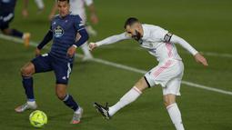 Striker Real Madrid, Karim Benzema menembak bola saat bertanding melawan Celta Vigo pada lanjutan La Liga Spanyol di stadion Alfredo Di Stefano, Minggu (3/1/2021). Real Madrid,  menggeser Atletico Madrid yang punya 35 poin, namun masih menyimpan tabungan tiga laga.(AP Photo/Manu Fernandez)