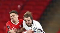 Pemain Inggris Harry Kane (kanan) memperebutkan bola dengan pemain Polandia Jan Bednarek pada pertandingan Grup I kualifikasi Piala Dunia 2022 di Stadion Wembley, London, Inggris, Rabu (31/3/2021). Inggris menang dengan skor 2-1. (Andy Rain/Pool via AP)