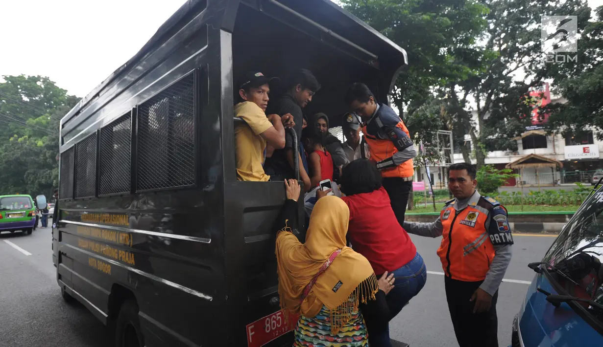 Warga menaiki kendaraan operasional Satpol PP saat aksi mogok sopir angkot 08 dan 09 di kawasan Tugu Kujang, Bogor, Selasa (13/11). Aksi mogok memprotes pengoperasian angkot modern tersebut membuat ratusan penumpang terlantar. (Merdeka.com/Arie Basuki)