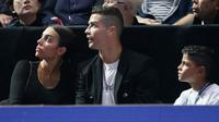 Pemain Juventus, Cristiano Ronaldo bersama sang kekasih, Georgina Rodriguez dan anaknya, Cristiano Jr menyaksikan Novak Djokovic menghadapi John Isner pada laga tenis dunia, ATP Finals 2018, di O2 Arena, London, Senin (12/11). (AP /Tim Ireland)