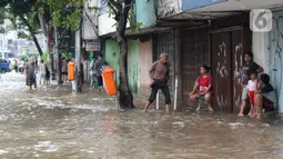 Warga berusaha melintasi genangan air di sebagian ruas Jalan Jatinegara Barat, Jakarta, Rabu Rabu (1/1/2020). Hujan yang mengguyur Jakarta sejak Selasa sore (31/12/2019) mengakibatkan banjir di sejumlah titik di Jakarta. (Liputan6.com/Helmi Fithriansyah)