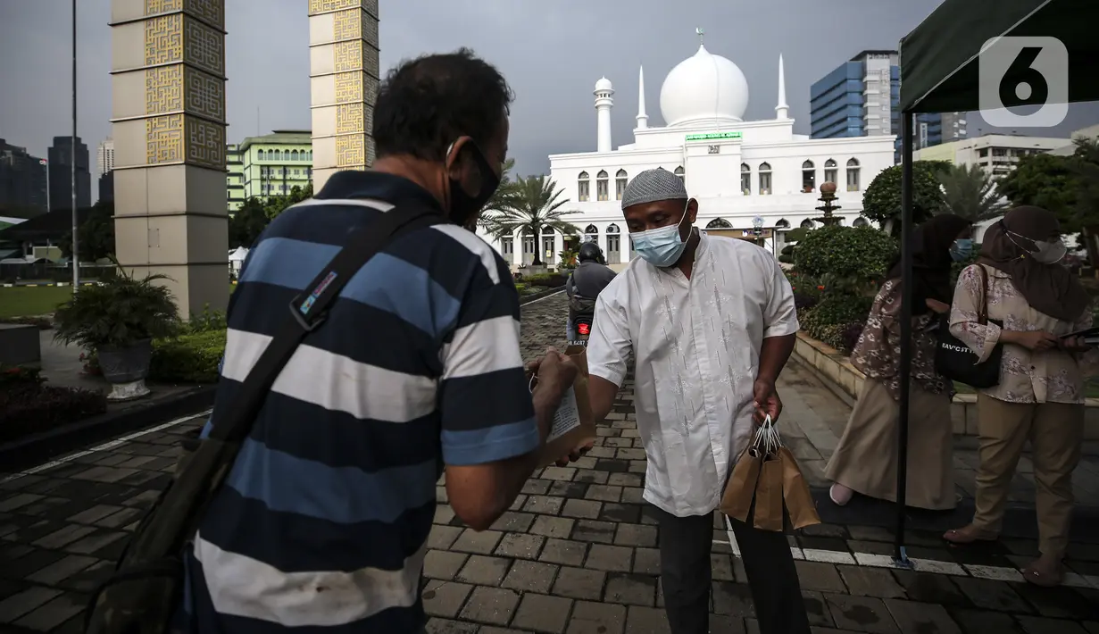 Petugas membagikan takjil kepada warga di Kompleks Masjid Al-Azhar, Jakarta, Kamis (15/4/2021). Pengelola masjid menyiapkan 500 bungkus takjil setiap harinya untuk pengendara yang dibagikan dengan sistem drive thru untuk mencegah penyebaran COVID-19. (Liputan6.com/Johan Tallo)