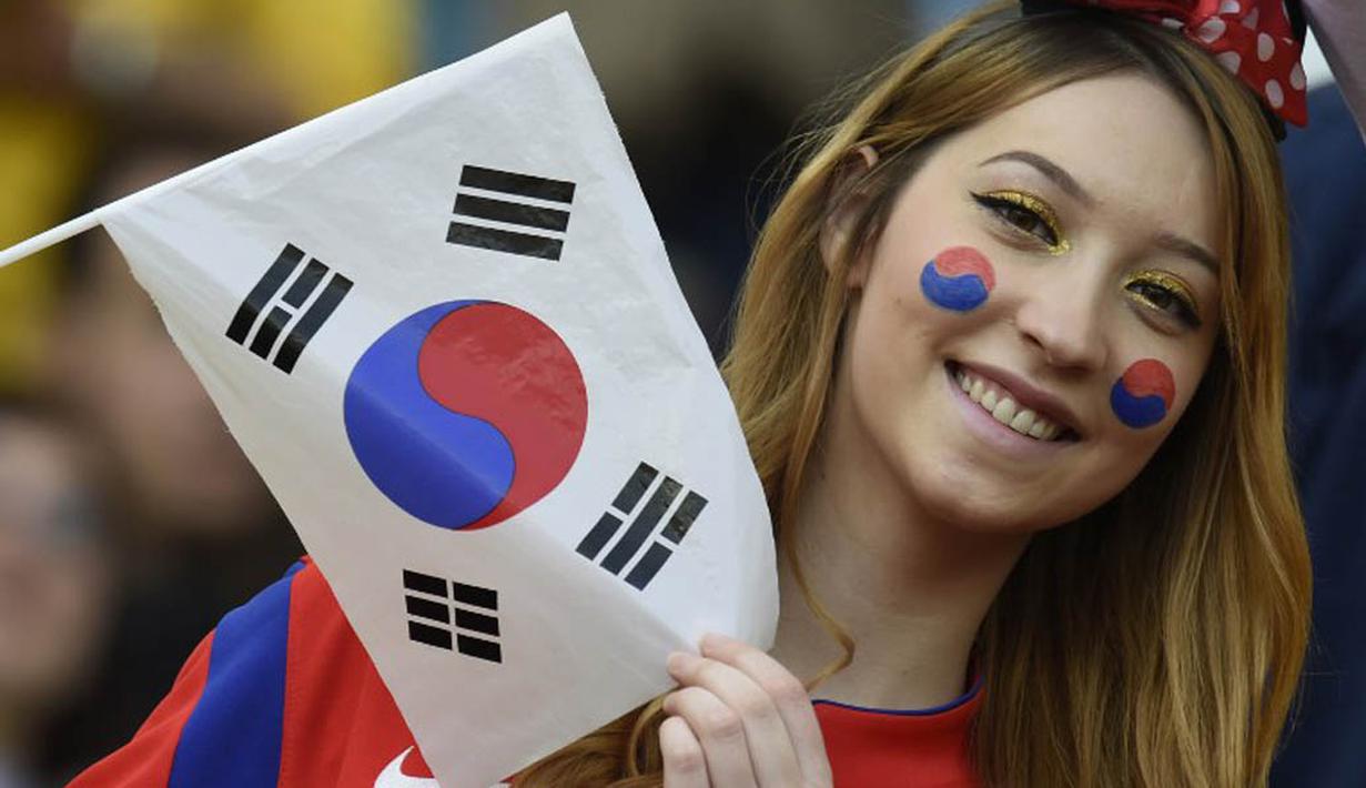 Seorang wanita cantik pendukung Korea Selatan mengibarkan bendera Korsel saat tim kesayangannya berlaga melawan Aljazair di Porto Alegre pada 22 Juni 2014 (AFP PHOTO/PHILIPPE DESMAZES)