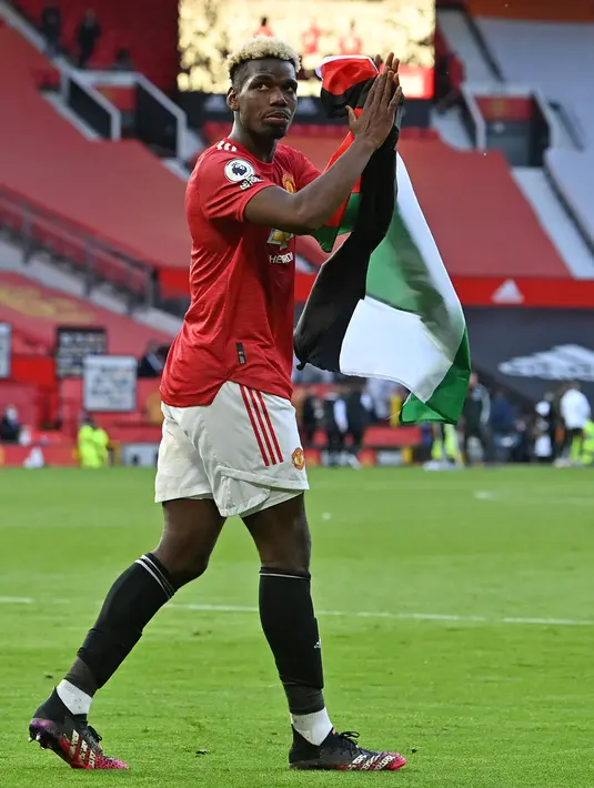 Gelandang Manchester United (MU), Paul Pogba terlihat memegang bendera Palestina pada pekan ke-37 Liga Inggris di Stadion Old Trafford, Rabu (19/5/2021) dinihari WIB. Momen itu terjadi usai laga Manchester United vs Fulham yang berakhir imbang 1-1. (Paul ELLIS/POOL/AFP)
