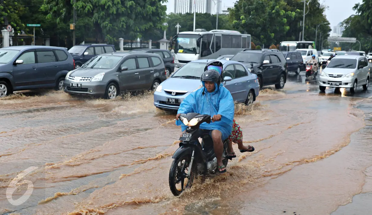 Pengendara sepeda motor melintasi genangan air yang merendam jalan di depan Istana Merdeka, Jakarta, Selasa (9/2). Hujan deras yang mengguyur kota Jakarta membuat sejumlah jalan protokol tergenang air. (Liputan6.com/Immanuel Antonius)