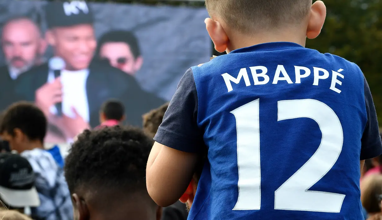 Seorang anak memakai jersey bernama bintang Prancis, Kylian Mbappe, saat jumpa fans markas AS Bondy di Paris, Rabu (17/10). Kunjungan ke klub pertamanya ini dilakukan setelah dirinya meraih gelar Piala Dunia 2018. (AFP/Franck Fife)