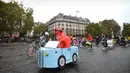 Seorang wanita mengemudikan sepeda yang dihias dengan kardus berbentuk mobil di Place de la Bastille, Paris, Prancis (1/10). Acara hari bebas kendaraan bermotor di Paris ini telah di gelar ketiga kalinya. (AFP Photo/Eric Feferberg)