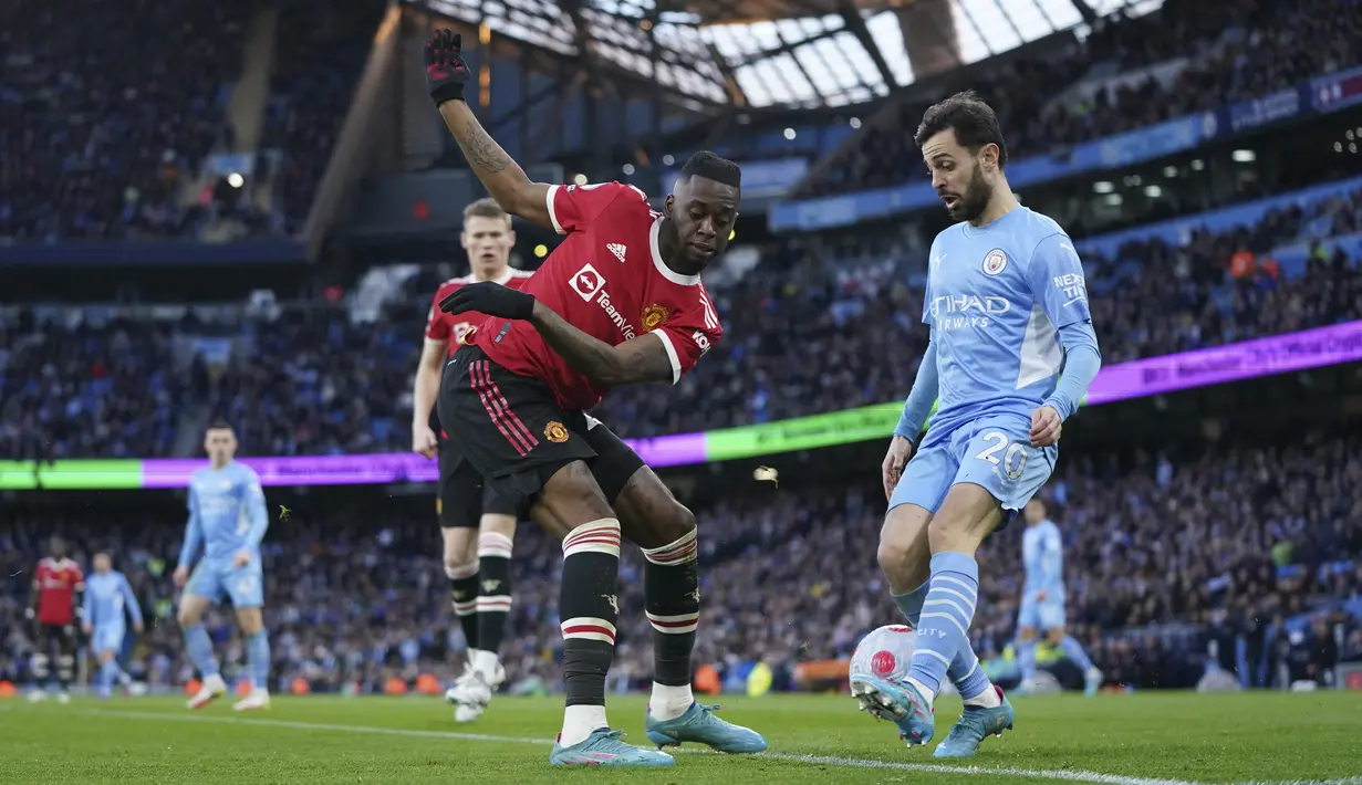Bek Manchester United (MU) Aaron Wan-Bissaka berebut bola dengan gelandang Manchester City Bernardo Silva dalam laga pekan ke-28 Liga Inggris 2021/2022, Minggu malam (6/3/2022) di Etihad Stadium. Manchester City menang telak 4-1 atas MU. (AP Photo/Jon Super)
