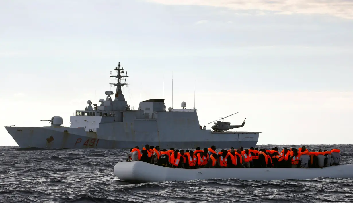 Perahu karet yang mengangkut para imigran Afrika terlihat di samping kapal angkatan laut Italia di Laut Meditarania, sekitar 36 mil laut dari lepas pantai Libya (2/2). (Reuters/Yannis Behrakis)