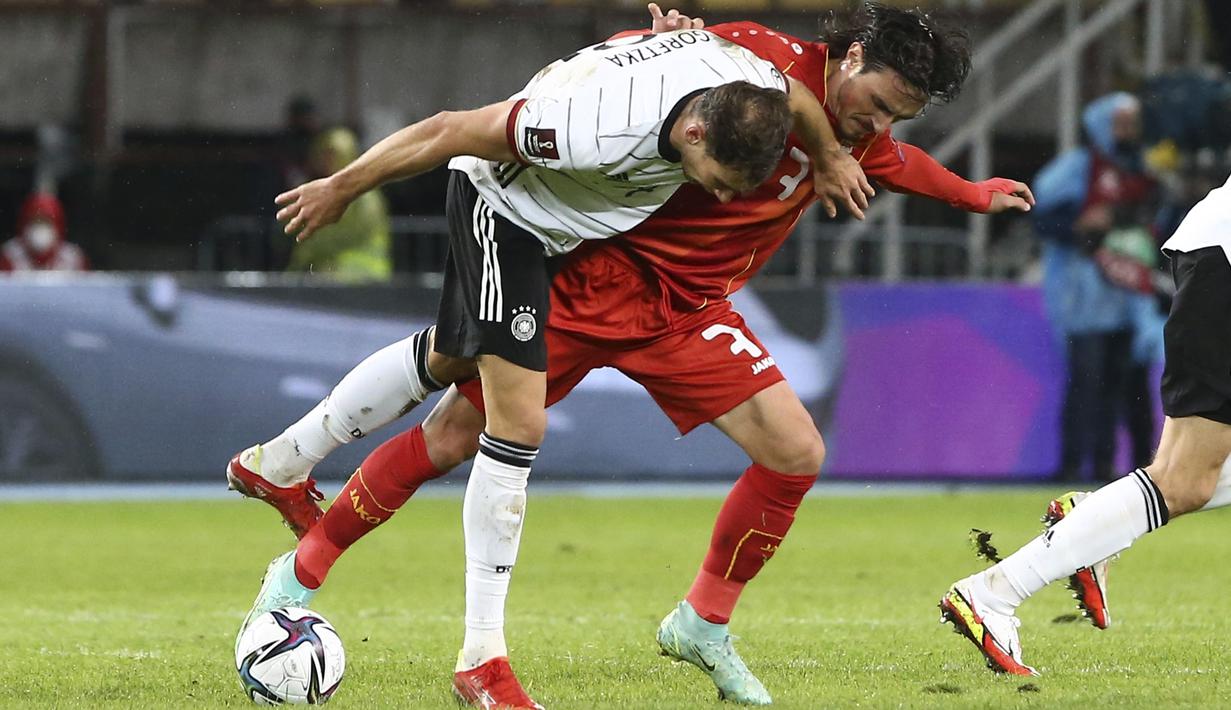 Gelandang Makedonia Utara Eljif Elmas dan gelandang Jerman Leon Goretzka berebut bola pada lanjutan Kualifikasi Piala Dunia 2022 zona Eropa Grup J di Tose Proeski National Arena, Selasa (12/10/2021) dini hari WIB. Jerman menghajar Makedonia Utara empat gol tanpa balas. (AP Photo/Boris Grdanoski)