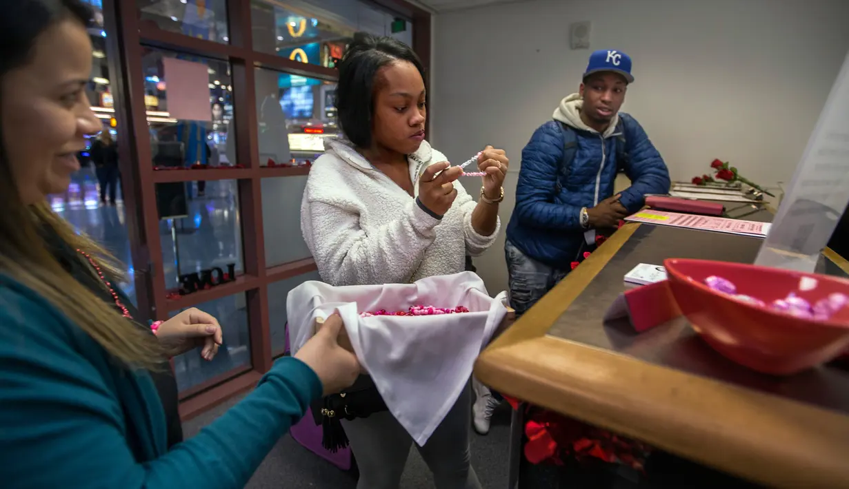 Pegawai menawarkan hadiah gelang kepada calon pasangan pernikahan kilat di Clark County Clerk's di Bandara Internasional McCarran di Las Vegas (12/2). Setelah melakukan prosedur,  surat nikah pun akan selesai dalam beberapa jam. (AFP/L.E. Baskow)