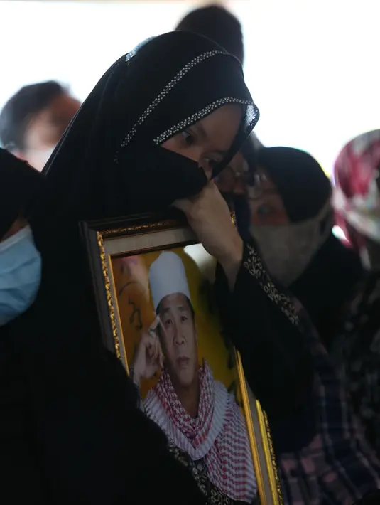 Seorang wanita mendekap foto pendakwah Ramdhan Effendi atau Anton Medan saat pemakaman di area Masjid Tan Kok Liong, Pondok Rajeg, Cibinong, Bogor, Jawa Barat, Selasa (16/3/2021). Anton Medan pernah menjadi Ketua Umum Persatuan Islam Tionghoa Indonesia (PITI). (Kapanlagi.com/Budy Santoso)