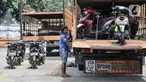 Petugas menaikkan sepeda motor milik peserta mudik gratis ke atas truk di Terminal Pulo Gadung, Jakarta, Selasa (26/4/2022). Pemprov DKI Jakarta mengadakan mudik gratis bagi warga yang memiliki KTP domisili DKI Jakarta dan telah vaksin COVID-19 booster. (merdeka.com/Iqbal S. Nugroho)
