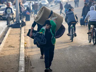 Warga Palestina membawa sejumlah barang saat mengungsi ke daerah yang lebih aman menyusul dimulainya kembali serangan Israel ke Rafah di Jalur Gaza selatan pada 1 Desember 2023. (MAHMUD HAMS/AFP)