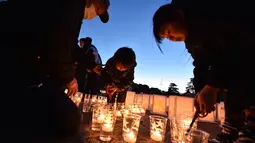 Sebuah keluarga menyalakan lilin dalam upacara peringatan bencana gempa tsunami di Natori, Prefektur Miyagi, Jepang (11/3). Masyarakat Jepang memperingati enam tahun gempa dan tsunami yang terjadi pada 2011 lalu. (AFP/Kazuhiro Nogi)