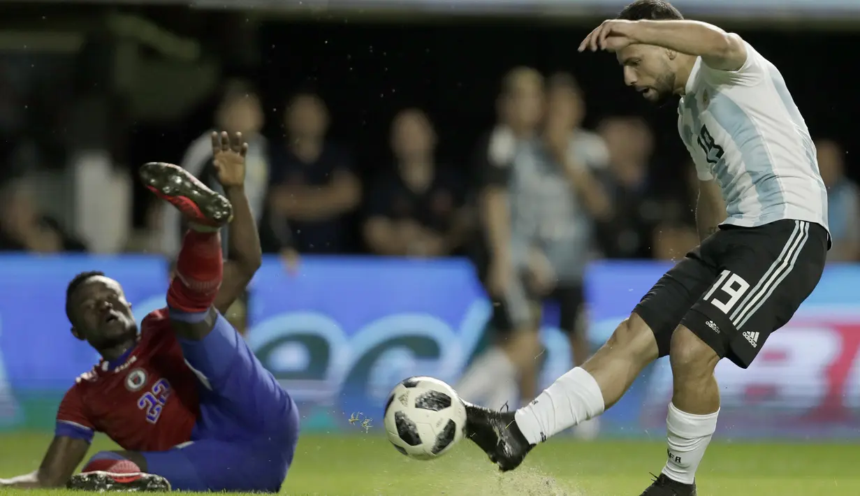 Pemain Argentina, Sergio Aguero melepaskan tembakan melewati pemain Haiti, Alex Junior Christian pada laga uji coba di Buenos Aires, Argentina, (29/5/2018). Argentina menang 4-0. (AP/Victor R. Caivano)