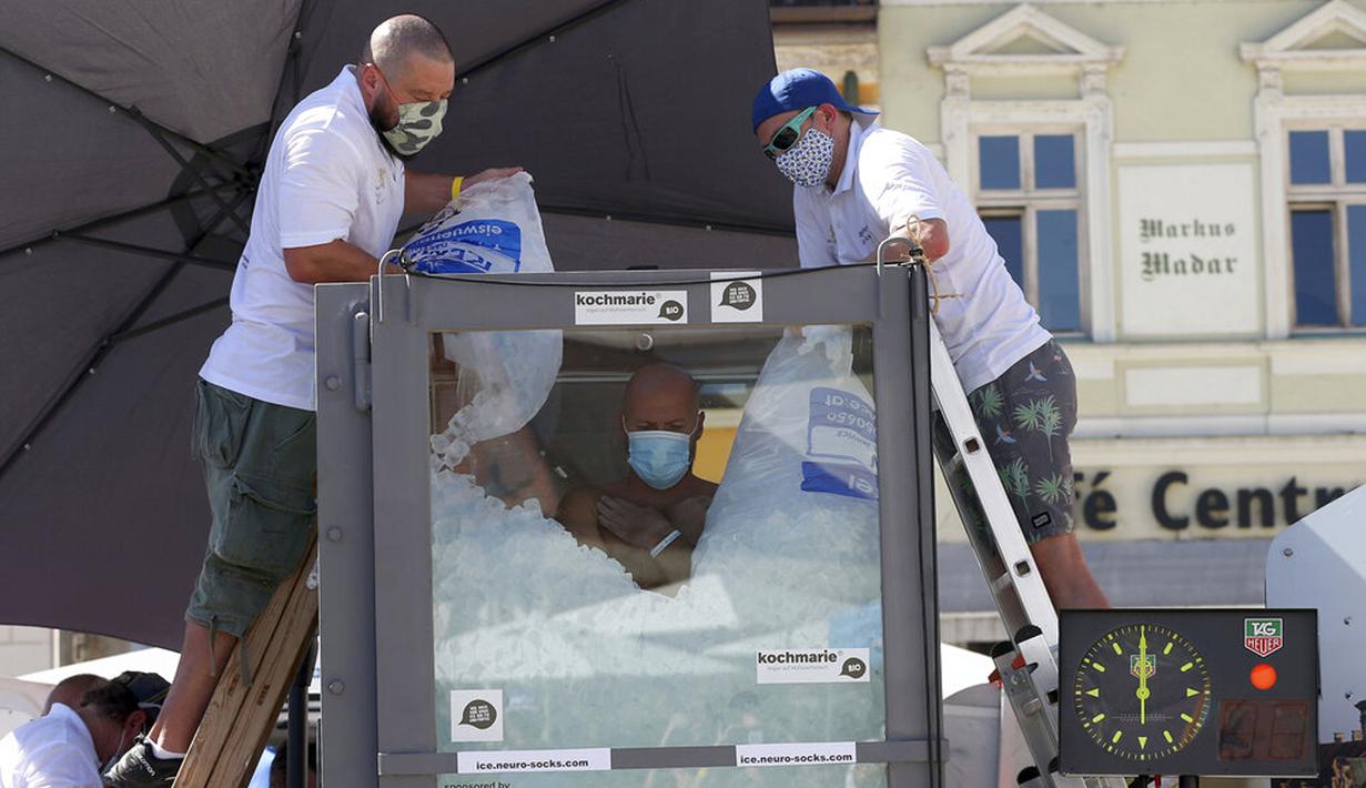 Perenang es Austria Josef Koeberl berdiri dalam kabin kaca berisi es di Melk, Austria, Sabtu (5/9/2020). Josef Koeberl berhasil memecahkan rekor dunia dengan berendam dalam es selama 2 jam, 30 menit, dan 57 detik. (AP Photo/Ronald Zak)