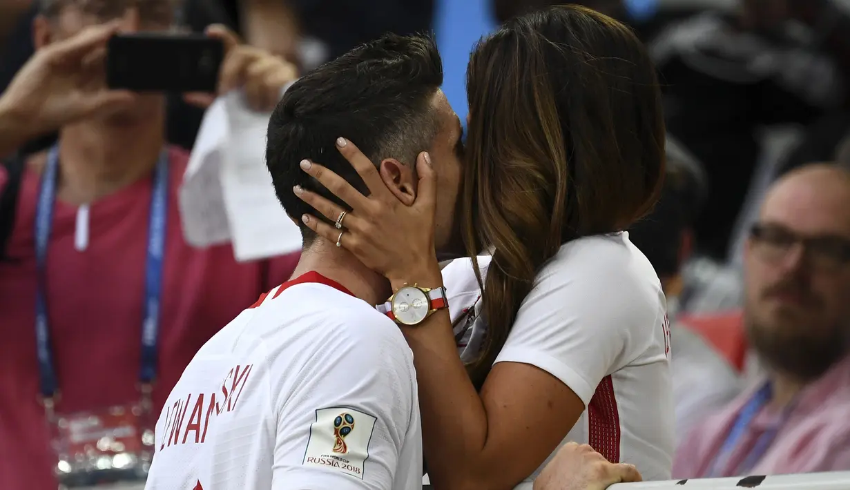 Kapten Polandia, Robert Lewandowski dicium mesra istrinya, Anna Lewandowska seusai dikalahkan Senegal pada pada penyisihan grup H di Piala Dunia 2018 di Stadion Spartak, Moskow, Selasa (19/6). Meski lebih diunggulkan, Polandia kalah 1-2. (FRANCK FIFE/AFP)