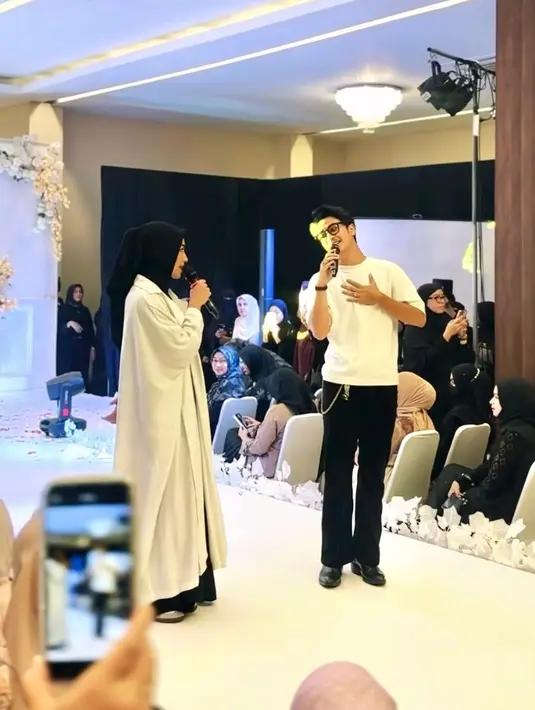 Sementara itu, Abidzar tampil kasual dengan kaus putih polos dan celana panjang warna hitam. Ia mempermanis tampilannya dengan aksesori rantai dan kacamata dengan bingkai warna hitam. [IG: @sintyamarisca].