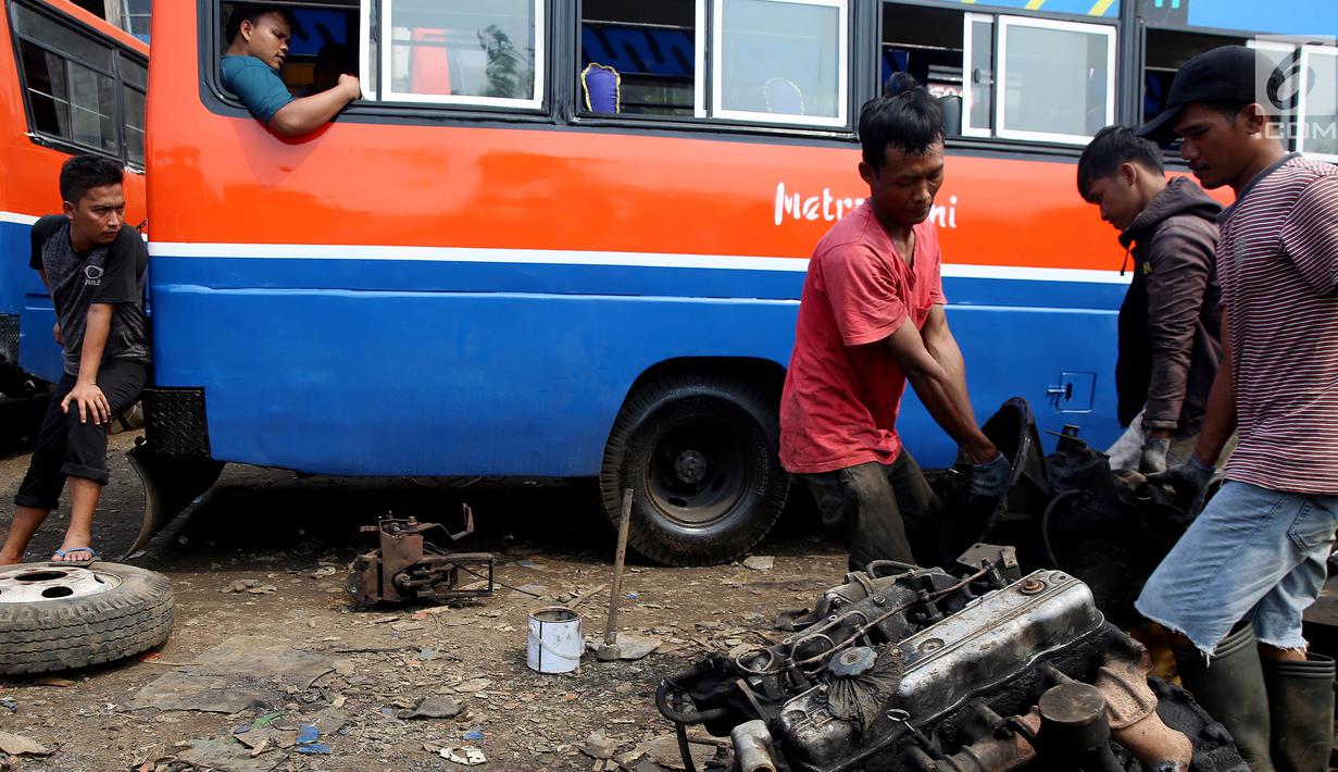 Pekerja mengangkut dan memindahkan bagian mesin dari angkutan Metromini di salah satu pool Metromini, Jalan Pulogebang, Jakarta, Rabu (3/1). Dari pada dikandangkan, mereka memilih untuk membongkar dan menjual ke pengepul. (Liputan6.com/JohanTallo)