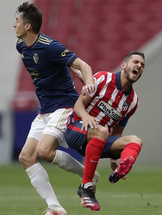 Gelandang Atletico Madrid, Koke menunjukkan rasa sakit saat berebut bola dengan penyerang Osasuna, Ante Budimir pada laga pekan ke-37 LaLiga di Wanda Metropolitano, Minggu (16/5/2021). Sempat tertinggal,  Atletico Madrid menang dramatis 2-1 atas Osasuna. (AP Photo/Manu Fernandez)
