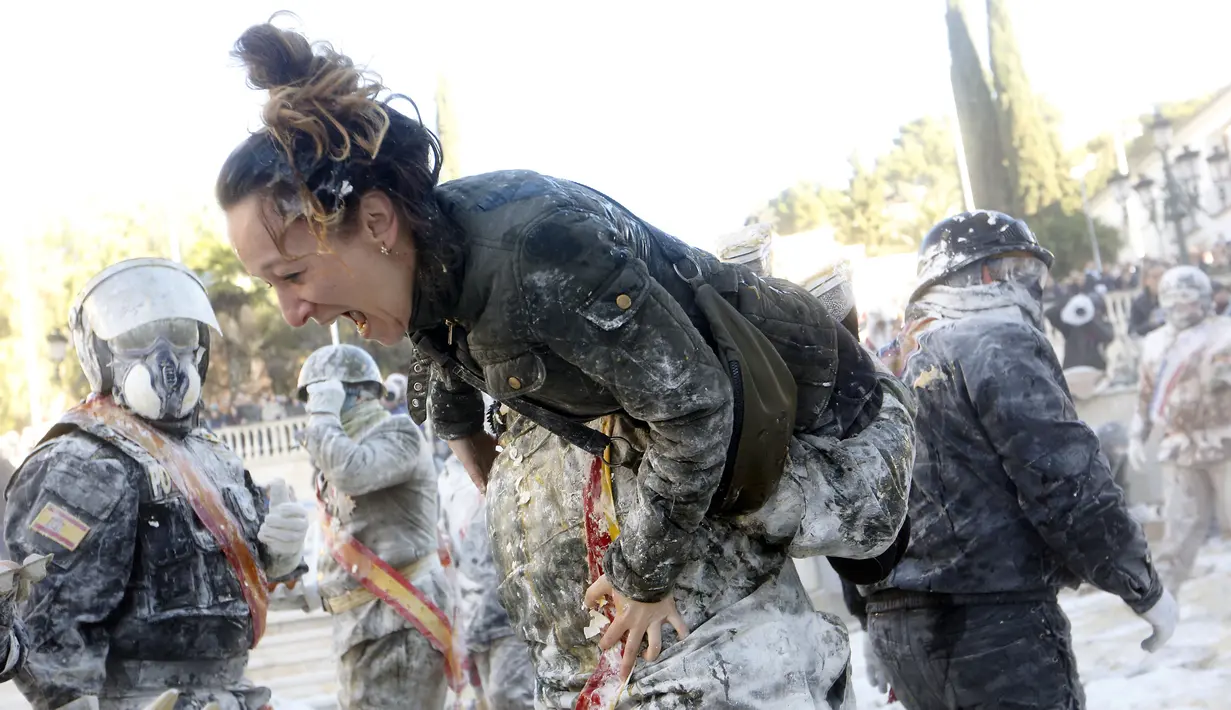 Seorang wanita dibopong oleh peserta festival Els Enfarinats di Kota Ibi, Spanyol, Sabtu (28/12/2019). Dalam festival yang sudah berlangsung selama 200 tahun ini para peserta bertempur menggunakan tepung, telur, dan petasan. (AP Photo/Alberto Saiz)