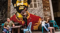 Ahmed Fathy (tengah) menuruni tangga dekat mural bintang Liverpool, Mohamed Salah di sebuah kedai kopi di pusat kota Kairo, 30 April 2018. Mural pemain timnas Mesir tersebut merupakan hasil karya Fathy. (AFP Photo/KHALED DESOUKI)