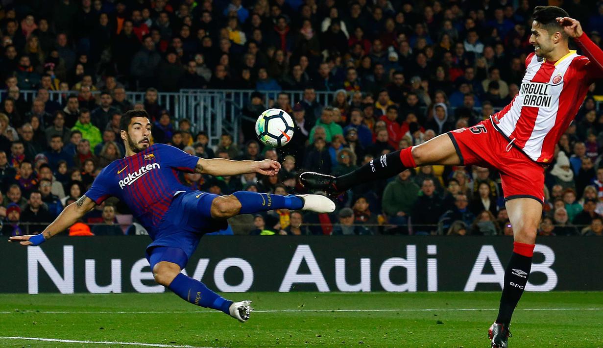 Penyerang Barcelona, Luis Suarez berebut bola dengan pemain Girona, Juanpe Ramirez saat bertanding pada La Liga Spanyol di stadion Camp Nou (25/2). Barcelona menang telak 6-1 atas Girona. (AP Photo/Manu Fernandez)