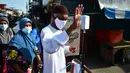 Seorang pria mengukur suhu tubuhnya sebelum memasuki pasar untuk membeli makanan, sebagai bagian dari upaya untuk menghentikan penyebaran virus corona Covid-19, selama bulan suci Ramadhan di provinsi selatan Thailand, Narathiwat (17/4/2021). (AFP/Madaree Tohlala)