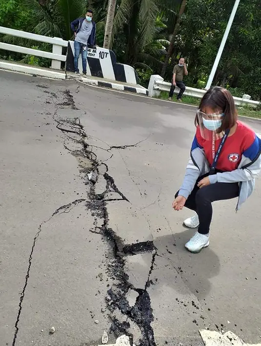 Relawan melihat retakan di jalan setelah gempa melanda Cataingan, Filipina tengah (18/8/2020). Badan seismologi Filipina menyatakan tidak ada potensi tsunami yang dipicu oleh gempa ini, namun warga diperingatkan akan adanya gempa susulan. (John Mark Lalaguna/Philippine National Red Cross via AP)