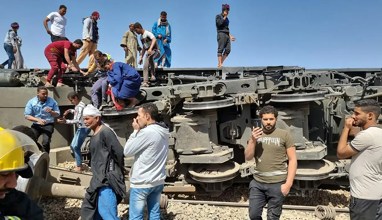 Orang-orang berkumpul di sekitar reruntuhan dua kereta yang bertabrakan di distrik Tahta di provinsi Sohag, sekitar 460 km (285 mil) selatan ibu kota Mesir, Kairo (26/3/2021). Tabrakan maut dua kereta di Mesir menewaskan sedikitnya 32 orang dan melukai sekitar 165 orang. (AFP)