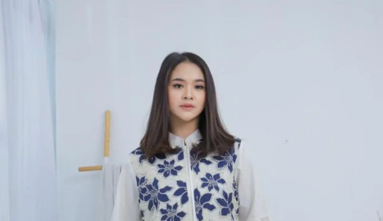 Perpaduan brokat putih bermotif bunga biru navy membuat tampilannya menjadi elegan. Dengan desain tanpa lengan luar yang dipadukan kemeja putih berlengan balon, tampilan ini memberikan kesan segar, modern, dan feminin. Cocok untuk dipakai ke acara semi-formal, kerja, maupun tampilan santai yang tetap stylish. [Dok/MAMAUTY]