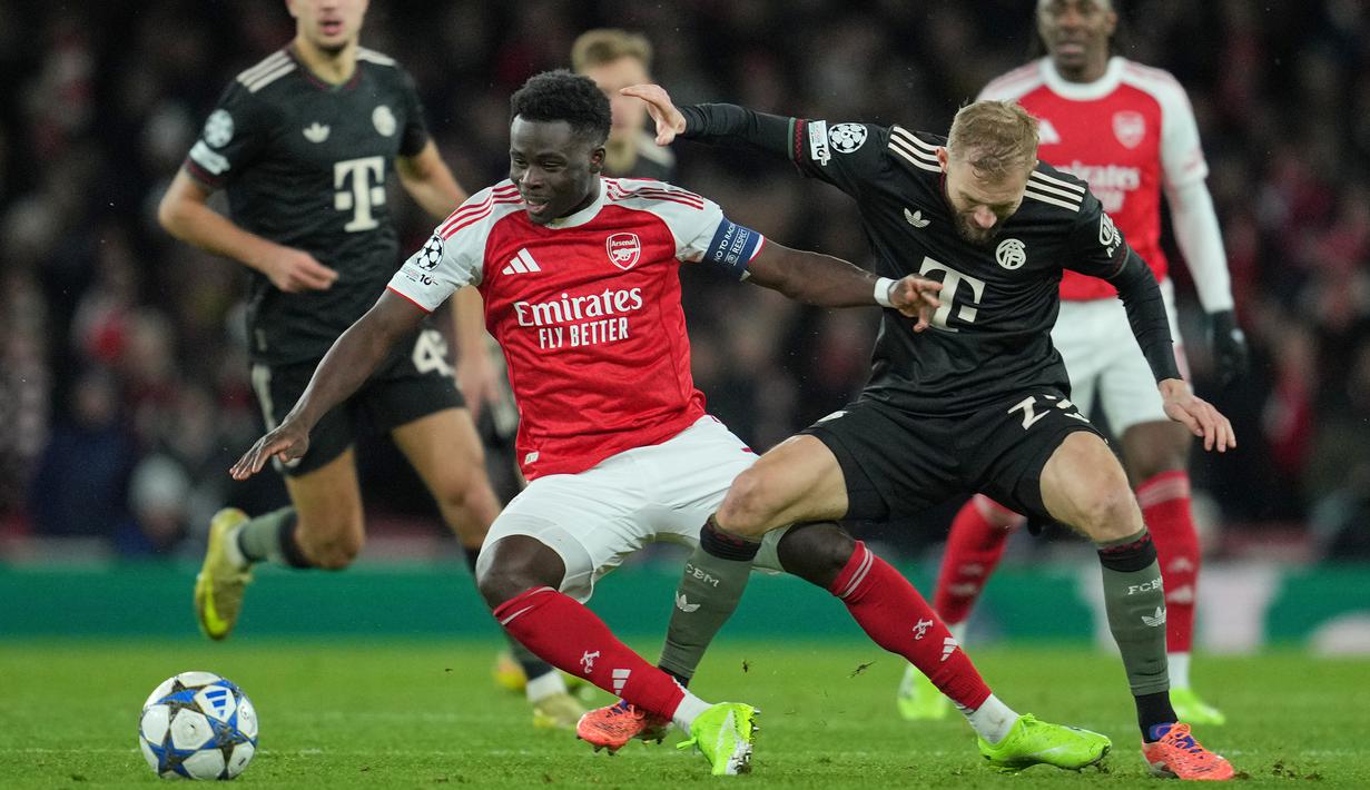 Pemain Arsenal, Bukayo Saka berebut bola dengan pemain Bayern Munchen, Konrad Laimer dalam laga Liga Champions 2025/2026 di Emirates Stadium, London, Rabu (26/11/2025) waktu setempat. (AP Photo/Kin Cheung)