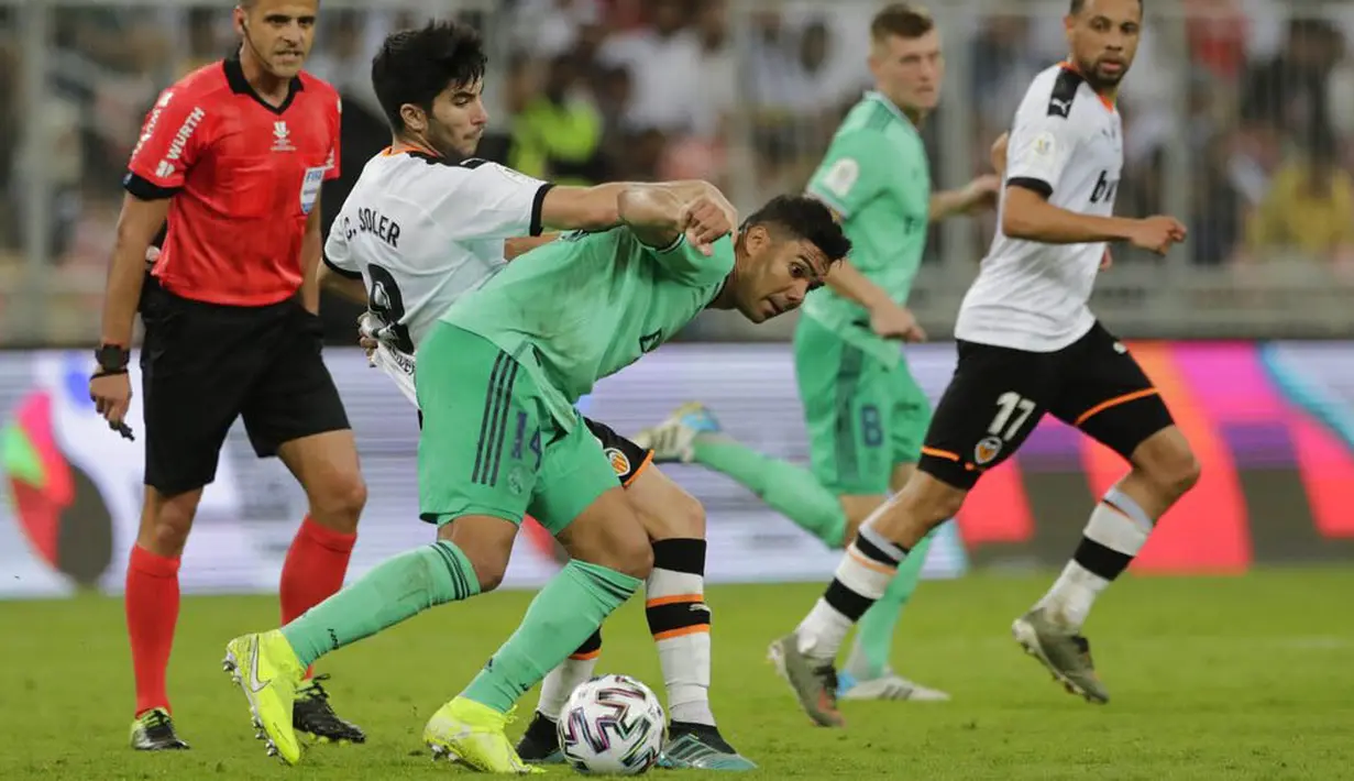 Gelandang Real Madrid, Casemiro, berebut bola dengan pemain Valencia, Carlos Soler, pada laga Piala Super Spanyol di Stadion King Abdullah Sport City, Arab Saudi, Rabu (8/1/2020). Real Madrid menang 3-1 atas Valencia. (AP/Amr Nabil)