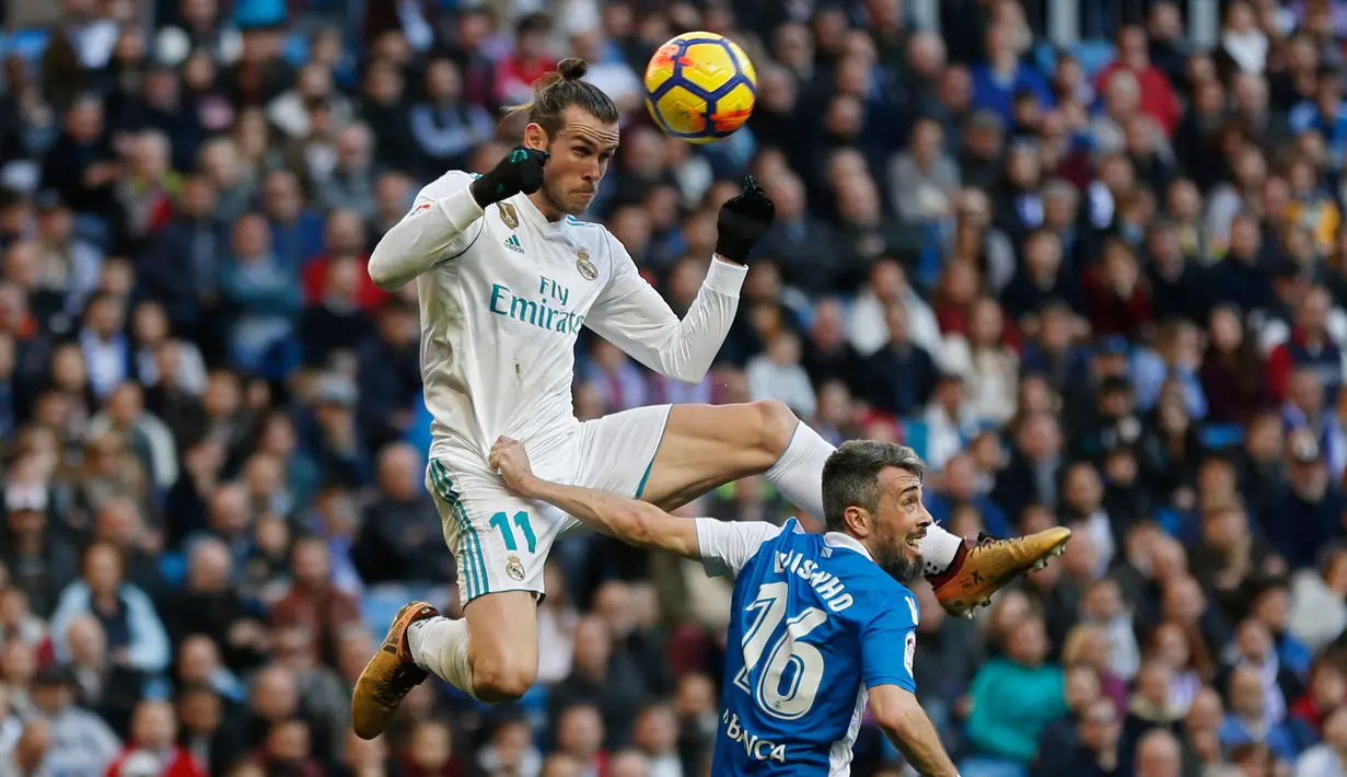 Pemain Real Madrid, Gareth Bale melompat untuk merebut bola dari pemain Deportivo La Coruna, Luisinho dalam lanjutan La Liga Spanyol di Santiago Bernabue, Senin (22/1). Real Madrid pesta kemenangan 7-1 atas Deportivo La Coruna. (AP/Francisco Seco)