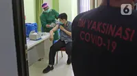 Petugas vaksinator menyuntikkan vaksinasi COVID-19 kepada tenaga kesehatan di RSUD Cengkareng, Jakarta, Kamis (14/01/2021). RSUD Cengkareng melakukan vaksinasi Covid-19 untuk para tenaga medis dan tenaga kesehatan yang bertugas. (Liputan6.com/Herman Zakharia)