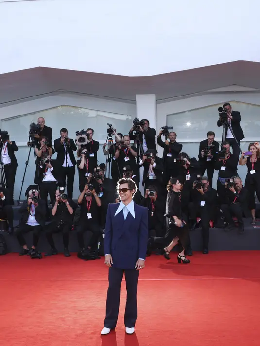Harry Styles berpose untuk para fotografer setibanya di pemutaran perdana film 'Don't Worry Darling' selama Venice Film Festival 2022 di Venesia, Italia, Senin (5/6/2022). Harry Styles mengenakan celana panjang longgar dengan warna yang sedikit lebih gelap. (Photo by Joel C Ryan/Invision/AP)