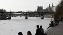 Orang-orang duduk di tepi sungai Seine di Paris, Rabu (3/3/2021).  Tingkat infeksi COVID-19 tetap tinggi selama beberapa minggu, dan pasien virus menempati 70% unit perawatan intensif negara itu. (AP Photo/Lewis Joly)
