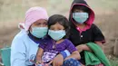 Sebuah keluarga mengenakan masker saat beraktivitas di kecamatan Kubu, Kabupaten Karangasem, Bali (27/11). Pejabat setempat juga mengimbau agar warga menggunakan masker untuk mengantisipasi adanya debu vulkanik. (AFP/Sonny Tumbelaka)