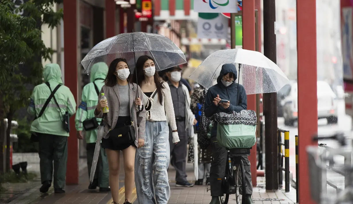 Dua wanita memakai masker wajah untuk mengekang penyebaran virus corona berjalan di area perbelanjaan Asakusa saat hujan turun di Tokyo (28/5/2021). Infeksi virus corona di Jepang masih belum melambat saat bersiap untuk menjadi tuan rumah Olimpiade hanya dalam waktu 50 hari. (AP Photo/Hiro Komae)