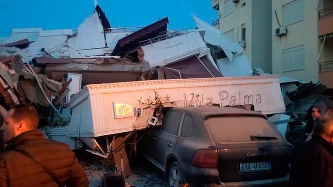 Sebuah mobil tetrimpa puing bangunan hotel yang rusak setelah gempa bumi di Durres, Albania barat, Selasa (26/11/2019). Gempa bumi bermagnitudo 6,4 mengguncang Albania, Selasa dini hari yang menyebabkan beberapa bangunan dan gedung permukiman runtuh. (AP Photo)